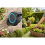 Carrete de manguera de pared RollUp S con manguera azul regando un jardín